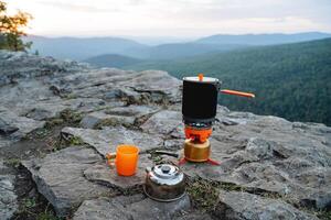 nel il sera su il montagna Là siamo piatti su il calcolo, un' turista cucina nel il campeggio, montagna escursioni a piedi attrezzatura per escursionismo. cena nel il montagne. foto