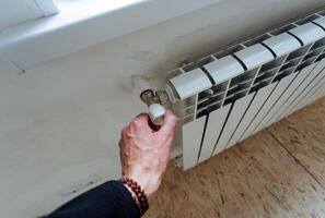 il mano regola il temperatura livello nel il termosifone, il rubinetto riduce il calore nel il Casa, liscio registrazione di il energia di il acqua flusso in il tubi. casa calore scambiatore. foto