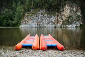 il catamarano sta su il banca di il fiume, gonfiabile rafting per rafting su montagna fiumi, turista attrezzatura per escursioni a piedi su il acqua, estremo su il fiume. foto