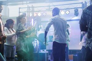 uomo e donna amici mostrando divertimento si sposta a danza battaglia mentre partying nel discoteca. ballerini improvvisando su pista da ballo illuminato con colorato luci mentre festeggiare nel club foto