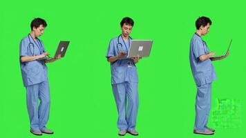 medico assistente navigazione per assistenza sanitaria trattamenti per Aiuto pazienti, utilizzando il computer portatile contro schermo verde sfondo. giovane infermiera naviga in linea siti web un ricerche per Salute sostegno. telecamera un. foto