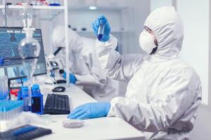 fare ricerca per trova un' vaccino per coronavirus vestito nel ppe completo da uomo. scienziato nel laboratorio indossare tuta fare ricerca e analizzando sostanza durante globale pandemia con covid19. foto