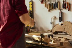 la lavorazione del legno specialista utilizzando Manuale carta vetrata per levigatrice legname bloccare, fabbricazione mobilia nel assemblaggio negozio durante lavoro spostare. tuttofare lucidatura superficie di pezzo di legna con abrasivo Materiale foto