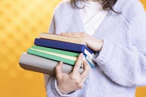 donna trasporto pila di libri, raccolta informazione per scuola esame, isolato al di sopra di studio sfondo, vicino su sparo. alunno Tenere mucchio di libri, preparazione scuola compiti a casa foto