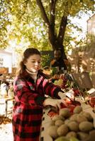 femmina consumatore navigazione e Selezione biologico fresco produrre a agricoltori mercato In piedi. nel raccogliere giusto Festival, giovane cliente shopping per localmente cresciuto frutta e verdure su raccogliere giusto bancarelle. foto