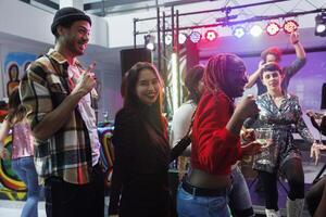 spensierato sorridente persone potabile alcool bevanda e avendo divertimento a discoteca festa nel discoteca. allegro giovane amici festeggiare e godendo vita notturna tempo libero attività nel club foto