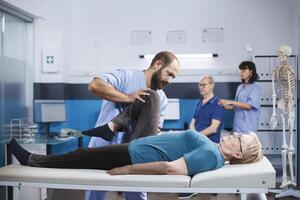 medico assiste pensionato donna con comune i problemi nel ottenendo ortopedico valutazione. medico fa chiropratica esercizi su anziano paziente chi ha ginocchio infortunio e è essere trattati per artrite. foto