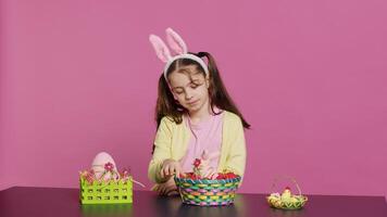 assonnato poco ragazza sbadigli mentre lei organizza Pasqua uova per festivo decorazioni, quasi caduta addormentato a il tavolo dove lei decora per primavera vacanza celebrazione. stanco scolaretta. telecamera un' foto