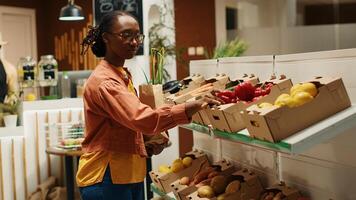 africano americano acquirente la scelta biologico produrre a partire dal casse, mettendo frutta e verdure nel un' carta Borsa per Acquista. donna shopping per naturale eco amichevole prodotti a Locale agricoltori mercato. telecamera 1. foto