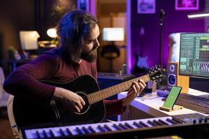 musicista giocando acustico strumento Il prossimo per schermo verde su smartphone, apprendimento nuovo accordi su stringhe per giocare su chitarra. artista produttore sviluppando il suo musicale abilità nel il suo casa studio. foto