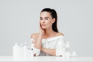 mezzo invecchiato, maturo donna mostrando cosmetico prodotti il branding modello. quotidiano cura della pelle e corpo cura routine. naturale cosmetico crema, siero, bianca bottiglie confezione, bio biologico Prodotto foto