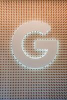 moderno lettera g design su strutturato parete, caldo retroilluminato splendore foto