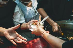 volontari Condividere cibo aiuto con il povero nel il Comunità. foto