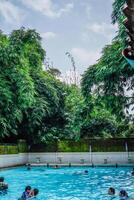 jepara, centrale Giava, aprile 14, 2024 - nuoto piscina cavalcate circondato di alberi siamo pieno di visitatori durante vacanze. foto