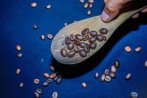 nero caffè fagioli siamo visto vicino su con un' di legno cucchiaio su un' nero stoffa. foto