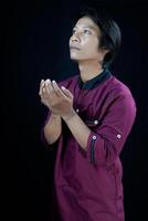 lato Visualizza di un' uomo raccolta il suo mani nel preghiera su un' nero sfondo. foto