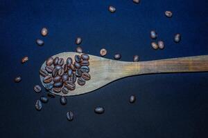 nero caffè fagioli siamo visto vicino su con un' di legno cucchiaio su un' nero stoffa. foto