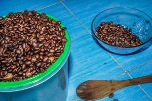 nero caffè fagioli nel un' ciotola su il verde pavimento. foto