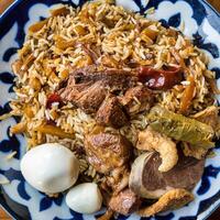 superiore Visualizza di un' piatto con uzbeko orientale pilaf con pezzi di agnello, cavallo carne, Quaglia riso e pollo uovo. centrale asiatico cucina. foto