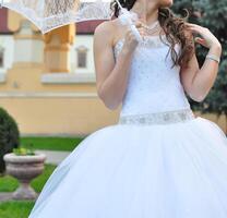 avvicinamento ritratto di giovane bellissimo sposa nel un' nozze vestito in piedi su un' verde campo e Tenere un' bianca ombrello foto