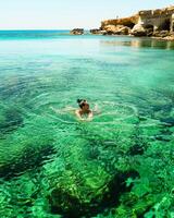 donna nuotate nel settentrionale Cipro ayia napa baia riva con cristallo chiaro blu mediterraneo acque e tranquillo paesaggio marino e roccioso pietra costa. mare grotte popolare viaggio destinazione foto