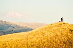 gioioso caucasico maschio ciclista in piedi di turismo bicicletta guardare per telecamera su superiore cima contento dopo raggiungendo obiettivi In piedi fiducioso godere spensierato stile di vita foto