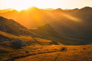 uomo e donna escursionisti nel distanza escursione su pista all'aperto su bellissimo tramonto nel autunno insieme. lento movimento contro sole attivo persone su trekking nel Caucaso montagne foto