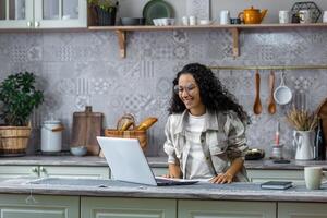 contento ispanico donna a casa guardare a il computer portatile sorridente e parlando remoto con gli amici. foto