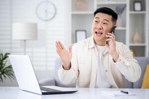maturo asiatico uomo parlando su il Telefono a casa, uomo Lavorando nel casa ufficio seduta a scrivania nel casa ufficio, contento e sorridente, consulenza clienti a distanza. foto