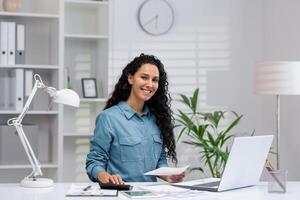 ritratto di un' sorridente ispanico donna Lavorando nel sua casa ufficio, dimostrando professionalità e fiducia. foto