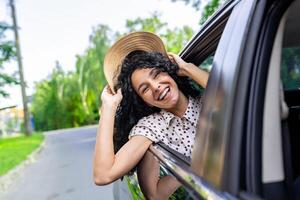 giovane ragazza in viaggio di macchina, ispanico donna con Riccio capelli guardare su il finestra, godendo vacanza e viaggio. foto