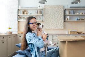 sorpresa regalo, giovane bellissimo asiatico donna ricevuto un' regalo di un' animale domestico Jack russell terrier cane, contento e sorridente foto