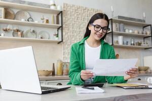 giovane sorridente donna progettista lavori a partire dal casa in linea. detiene documenti, piani, disegni nel il suo mani foto