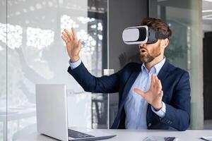 uomo d'affari nel completo da uomo utilizzando vr cuffia a ufficio scrivania, sperimentare virtuale la realtà tecnologia con espressive mano gesti. foto