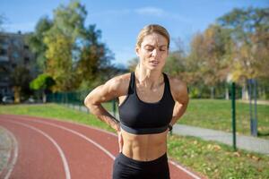 focalizzata donna nel abbigliamento sportivo assunzione un' rompere su il in esecuzione traccia, mostrando determinazione e fitness viaggio. foto