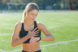 focalizzata donna nel abbigliamento sportivo monitoraggio sua cuore Vota mentre attraente sua respiro dopo un' esigente esercizio sessione fuori. foto