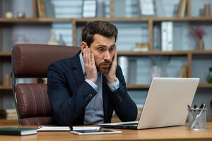 maturo uomo d'affari nel in profondità concentrazione Lavorando su il computer portatile nel un' casa ufficio. professionale guardare finanziario focalizzata su schermo. foto