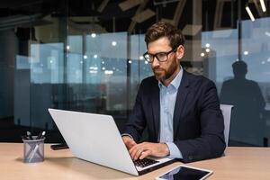 grave uomo d'affari Lavorando dentro ufficio a opera, maturo capo nel attività commerciale completo da uomo seduta a computer e tavolo, anziano uomo pensiero. foto