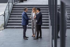 incontro di tre riuscito attività commerciale le persone, diverso sognare squadra uomo e donna al di fuori ufficio costruzione, saluto e tremante mani, esperto professionisti specialisti nel attività commerciale tute parlando foto