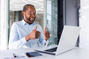 chiamata su in linea incontro, africano americano uomo d'affari capo parlando per colleghi partner mostrando il computer portatile telecamera pollici su soddisfatto con squadra opera realizzazione risultati. foto