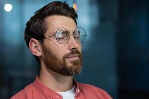 vicino su di maturo pensiero uomo d'affari Meditare e pensiero con chiuso occhi a posto di lavoro dentro ufficio, uomo nel rosso camicia riposo e respirazione. foto