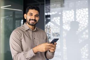 un' uomo è sorridente e Tenere un' cellula Telefono foto