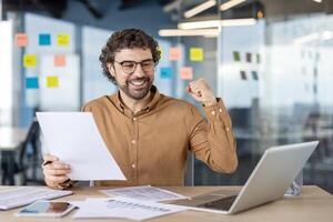 finanziere riuscito contabile dentro il ufficio a il posto di lavoro, contento uomo celebra vittoria, successo carta opera, uomo d'affari detiene rapporto nel mani, soddisfatto con risultati di risultato. foto