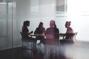 ritratto di un' gruppo di professionisti seduta in giro un' conferenza tavolo nel un ufficio spazio con trasparente bicchiere partizioni foto