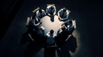 un' gruppo di uomini d'affari si siede in giro un' il giro tavolo a un' attività commerciale convenzione nel il mezzo di un' debolmente illuminato camera foto