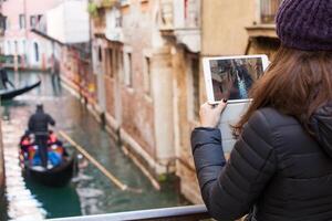 giovane ragazza utilizzando un' tavoletta per prendere immagini di gondole di Venezia. foto
