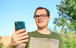 uomo con occhiali e verde maglietta su chiamata a partire dal il suo cellula Telefono a parco foto
