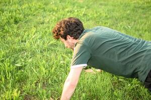 giovane uomo con verde maglietta fare sollevamento nel parco foto