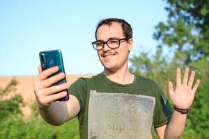 uomo con occhiali e verde maglietta su chiamata a partire dal il suo cellula Telefono a parco foto