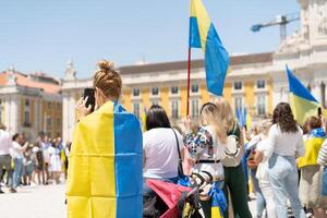 Portogallo, Lisbona aprile 2022 il dimostrazione su commercio piazza nel supporto di Ucraina e contro il russo aggressione. manifestanti contro di russia guerra molti persone con ucraino bandiere. foto